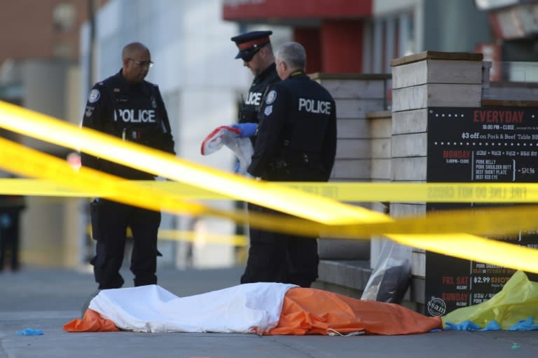 Police officers stand near one of the bodies on the street after a truck drove up on the curb and hit several pedestrians in Toronto