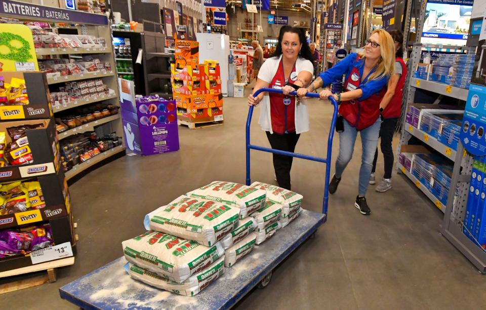 Lowe's Assistant Store Managers Brandy Fincher and Heather Fox wheel ten 50-pound bags of sand toward Melbourne resident Pat Alderman's truck Sunday morning in West Melbourne.