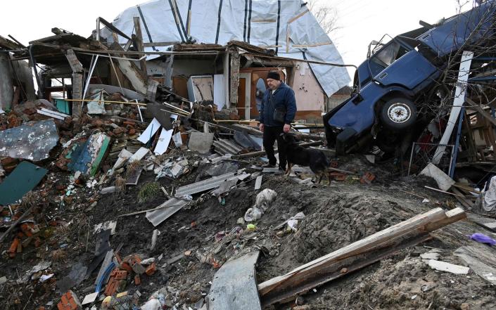 Local resident Vitalii, 41, looks at a rocket explosion crater in the yard of his house in the Tsirkuny village, Kharkiv region. - SERGEY BOBOK/AFP