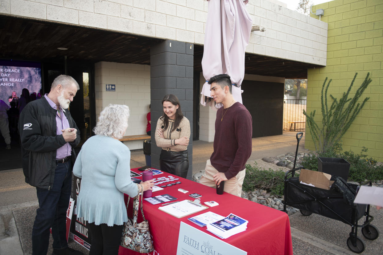 Elizaveta Kuznetsov, center, and Jacob Chacon, two Turning Point representatives, speak with churchgoers outside Jesus People Church in Scottsdale, Ariz., March 27, 2024. (Caitlin O