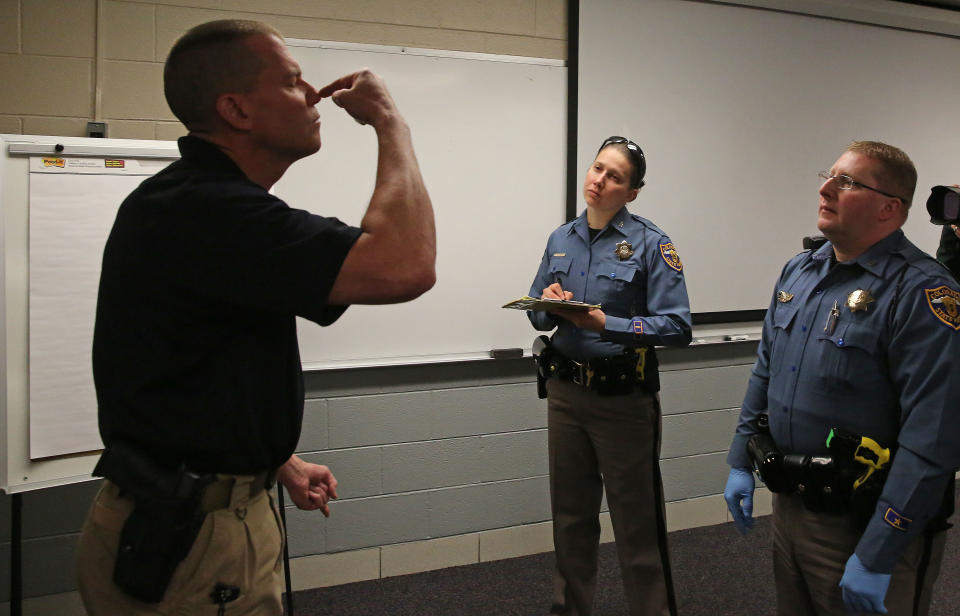 Simulating a roadside investigation of a potentially intoxicated driver, Colorado State Trooper Sgt. David Blatner, left, pretends to be high and struggling to touch his nose with his eyes closed as he trains troopers Carrie Jackson, center, and Toby Cox in a several week long Drug Recognition Expert class, at the Colorado State Patrol Training Academy, in Golden, Colo., Thursday March 6, 2014. The ongoing training is happening as Colorado struggles to keep accurate statewide records on marijuana-impaired drivers, with state police chiefs saying they need more money to train officers in recognizing stoned drivers. (AP Photo/Brennan Linsley)