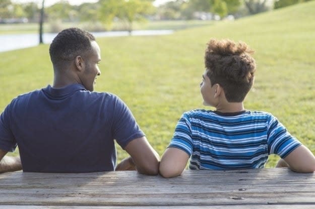 A father and his son sit on a park bench