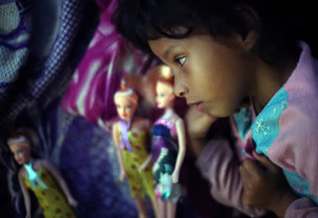 Genesis Cordona, a six-year-old migrant girl from Honduras, part of a caravan of thousands from Central America en route to the United States, lays next to her dolls as she rests in Santiago Niltepec, Mexico, October 29, 2018. REUTERS/Hannah McKay