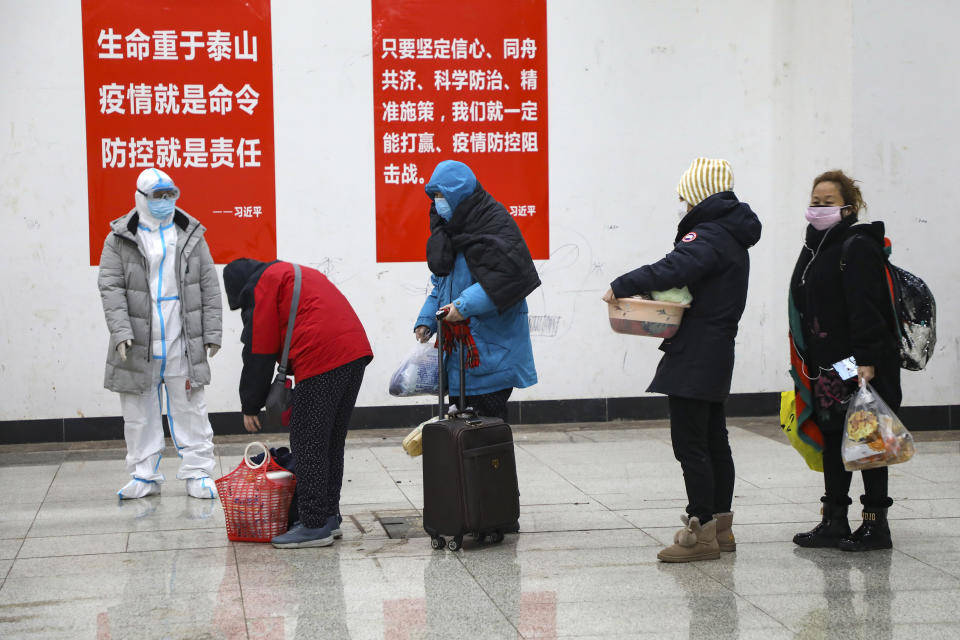 In this Wednesday, Feb. 5, 2020, photo, a medical worker in a protective suit looks at patients who diagnosed with the coronaviruses arrive at a temporary hospital which transformed from an exhibition center in Wuhan in central China's Hubei province. Ten more people were sickened with a new virus aboard one of two quarantined cruise ships with some 5,400 passengers and crew aboard, health officials in Japan said Thursday, as China reported 73 more deaths and announced that the first group of patients were expected to start taking a new antiviral drug. (Chinatopix via AP)