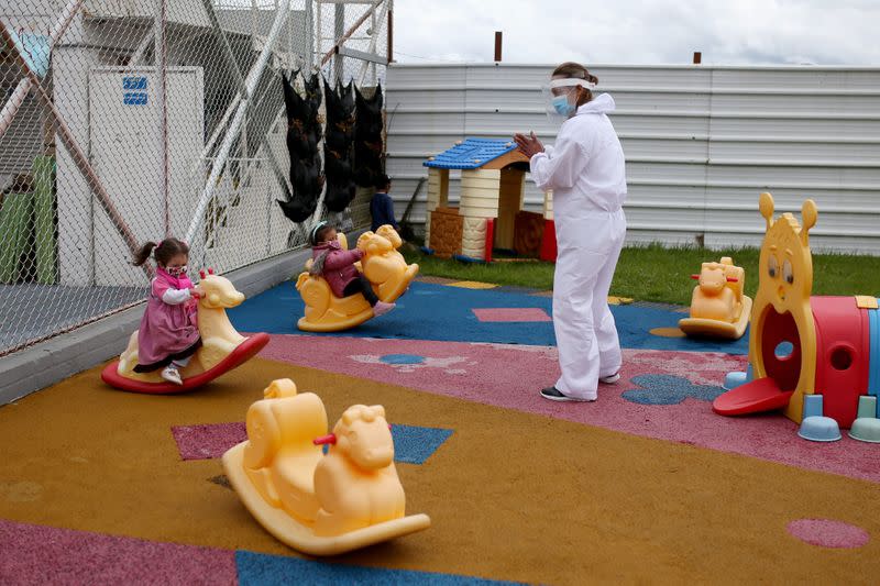 A teacher wearing protective gear plays with her students in a kindergarten, during the reactivation of several economic sectors after the end of quarantine due to the coronavirus disease (COVID-19), in Bogota