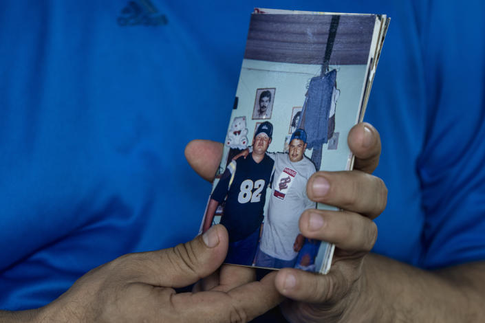 Jesus Joya holds a snapshot of himself, pictured right, and his younger brother Henry, who was removed from his his home by police and detained under the ongoing "state of exception", in San Salvador, El Salvador, Wednesday, Oct. 12, 2022. Henry is one of at least 80 people arrested under the state of exception that have succumbed without being convicted of anything. (AP Photo/Moises Castillo)