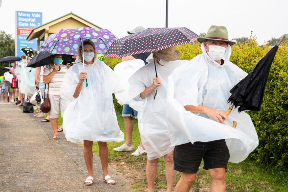 People wearing rain ponchos are seen lining up at a Covid-19 testing site at Mona Vale Hospital in Sydney, Australia.