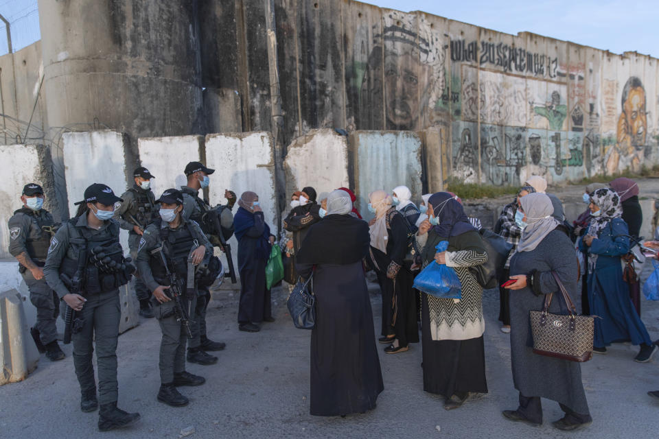 Palestinian women wait to cross the Qalandia checkpoint between the West Bank city of Ramallah and Jerusalem, to attend the first Friday prayers in al-Aqsa mosque, during the Muslim holy month of Ramadan, Friday, April 16, 2021. A limited number of Palestinian residents who carry both a travel permit and a vaccination document, are allowed to cross into Israel to attend the prayers at al-Aqsa mosque, due to the coronavirus pandemic. (AP Photo/Nasser Nasser)