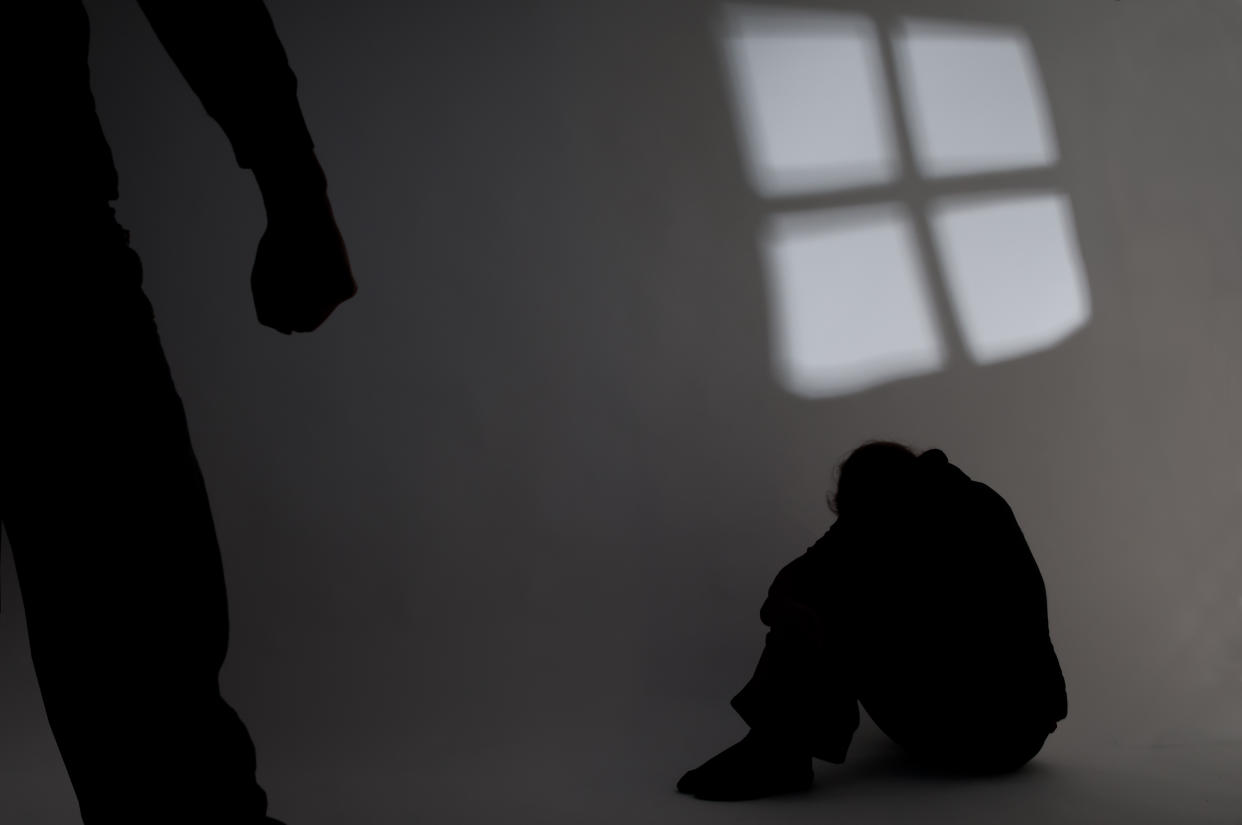 A person with clenched fist in front of a crouched figure. (PHOTO: Getty Images)