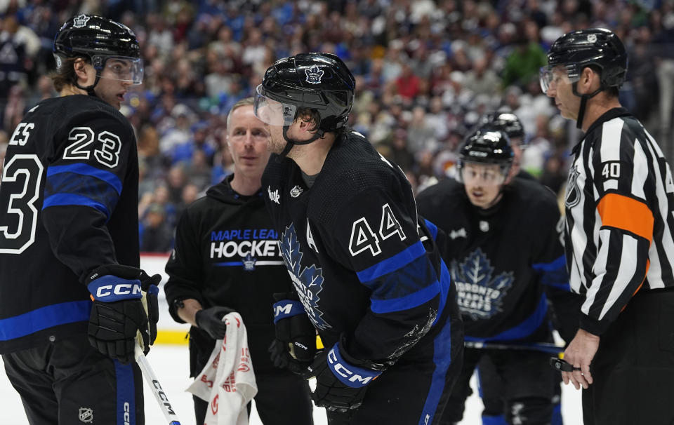 Toronto Maple Leafs defenseman Morgan Rielly (44) skates off the ice after being injured while stopping a shot as left wing Matthew Knies, left, and referee Steve Kozari look on in the third period of an NHL hockey game against the Colorado Avalanche Saturday, Feb. 24, 2024, in Denver. (AP Photo/David Zalubowski)