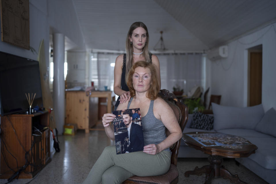 Evgenia Kozlov holds up a portrait of her 27-year-old son, Andrey Kozlov, while Kozlov's girlfriend Jenifer Master stands behind her in their family house in Rishon Lezion, Israel, Thursday, Oct. 26, 2023. Kozlov, a Russian citizen, was abducted by Hamas militants from the "Nova" Music Festival near Kibbutz Re'im during the militant group's unprecedented attack on Israel on Oct. 7 that resulted in the killing of 1,400 people and the abduction of over 220. (AP Photo/Ohad Zwigenberg)