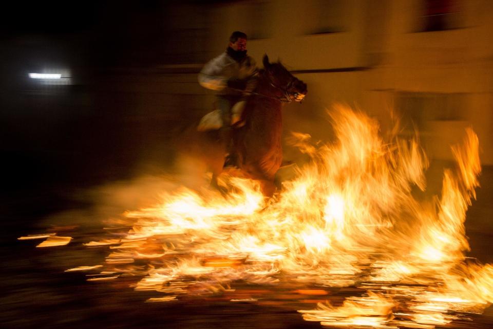 Un hombre cabalga a través del fuego como parte de un ritual en honor a San Antonio Abad, el patrón de los animales, en San Bartolomé de Pinares, a 100 kilómetros de Madrid, España, el lunes 16 de enero de 2017. En la víspera del Día de San Antonio, cientos cabalgan sus caballos a través de las calles del pequeño pueblo durante Las Luminarias, una tradición que data de hace más de 500 años y significa la purificación de los animales con el humo del fuego que los protege de los años por venir. (AP Foto/Emilio Morenatti)