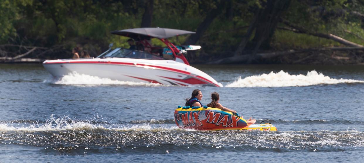 A wake boat passes girls in an inflatable tube being towed on the Mississippi River near Nelson, Wisconsin.
