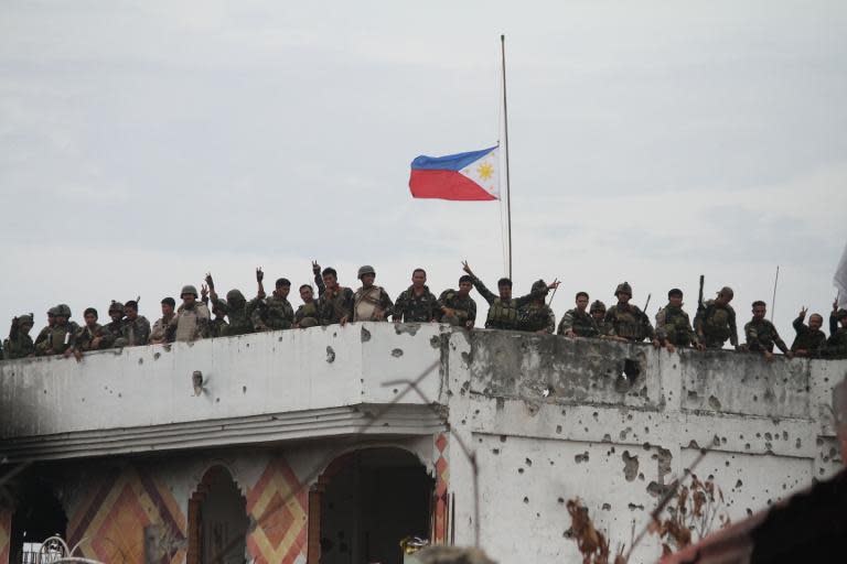 Philippine soldiers celebrate on the roof of a damaged house following heavy fighting against Islamist militants in Zamboanga on September 28, 2013