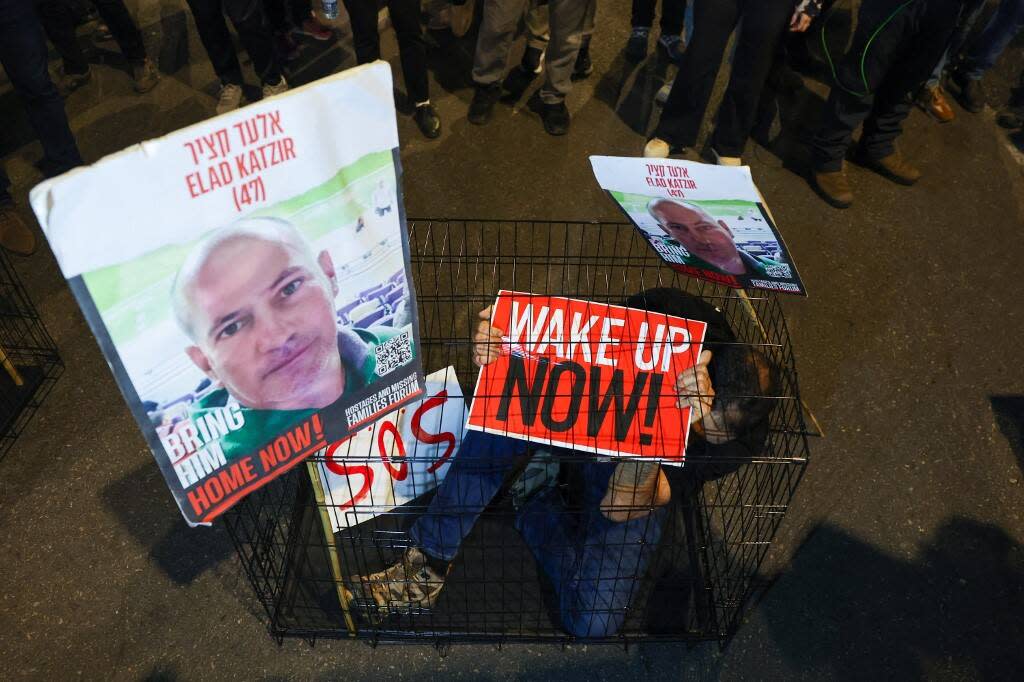 Un homme est assis dans une cage avec des portraits de l’otage israélien de 47 ans, Elad Katzir, lors d’une manifestation à Tel Aviv, le 26 mars 2024.