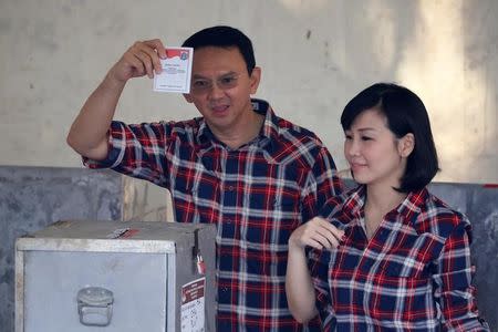Governor of Indonesia's capital Basuki Tjahaja Purnama (L) shows his ballot as he stands beside his wife Veronica Tan during an election for Jakarta's governor in Jakarta, Indonesia, February 15, 2017. REUTERS/Beawiharta