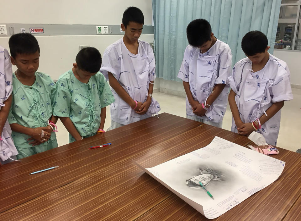 <em>The boys bow their heads after writing messages on the drawing (Reuters)</em>