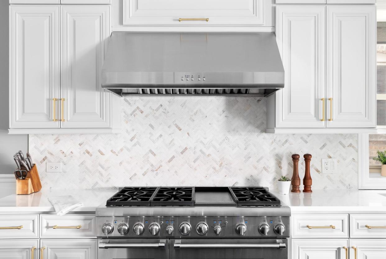 Modern bright, white marble kitchen scene with stove and oven