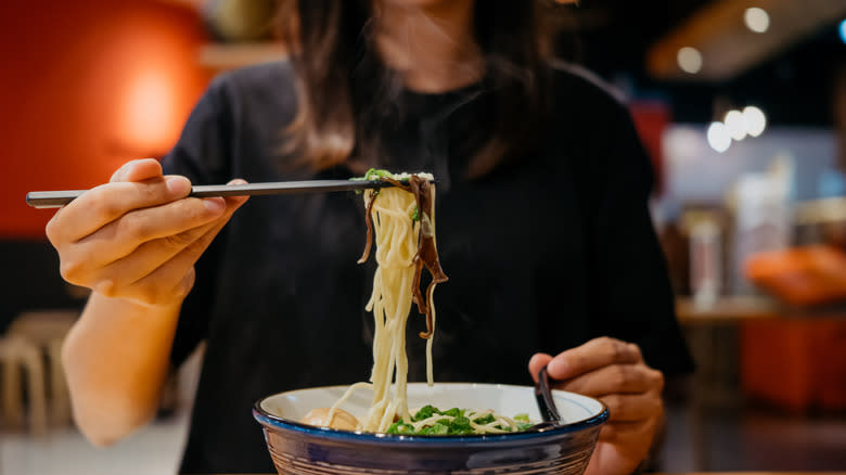 Woman eating ramen with chopsticks