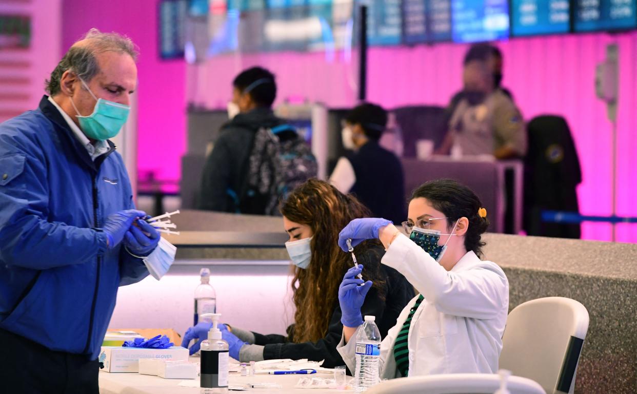 Pharmacists load syringes with the Covid-19 vaccine for administration at a pop-up clinic in the international arrivals section of Los Angeles International Airport in Los Angeles, California.