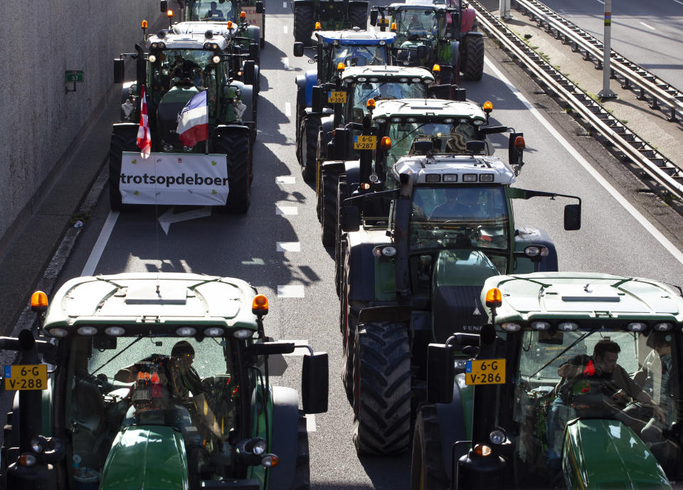 Protesting farmers on tractors, one with a sign reading "Proud of the Farmer", block a main road leading to the center of The Hague, Netherlands, Wednesday, Oct. 16, 2019. Thousands of Dutch farmers protest over the Netherlands efforts to drastically reduce emissions of greenhouse gases. Among the farmers' demands are that the government does not further reduce the number of animals they can keep. (AP Photo/Peter Dejong)