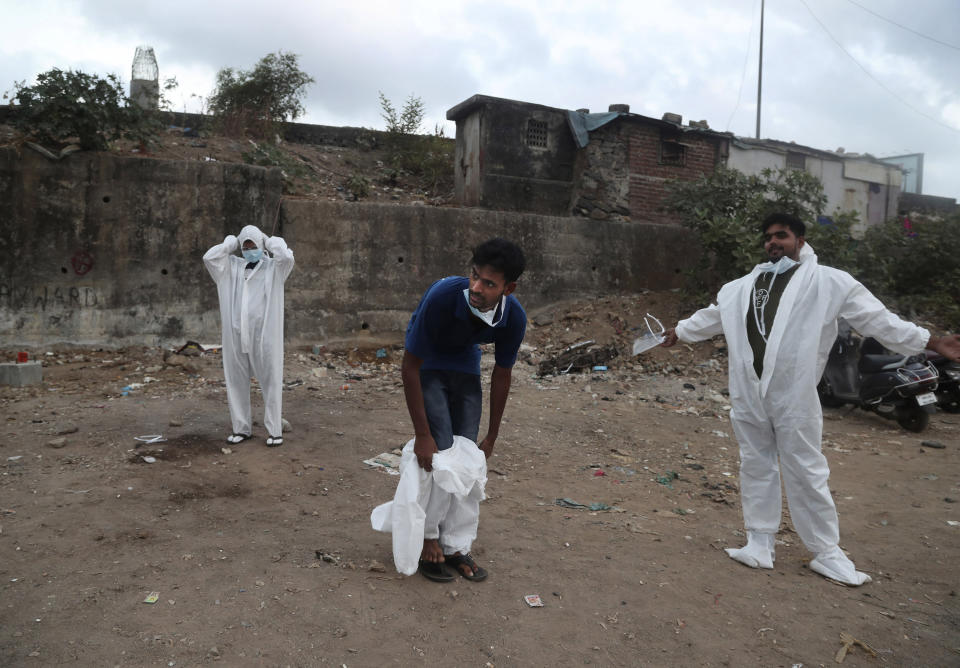 Izhaar Hussain Shaikh, center, an ambulance driver who works for HelpNow, an initiative to help the stretched services of first responders, gets out of his protective suit, after dropping a COVID-19 patient at a hospital in Mumbai, India May 28, 2020. It’s an exhausting job and Shaikh's daily shifts are grueling, sometimes even stretching to 16 hours. For a city that has a history of shortage of ambulances and where coronavirus pandemic has claimed hundreds of lives, putting the health care system under immense strain, every help counts. (AP Photo/Rafiq Maqbool)