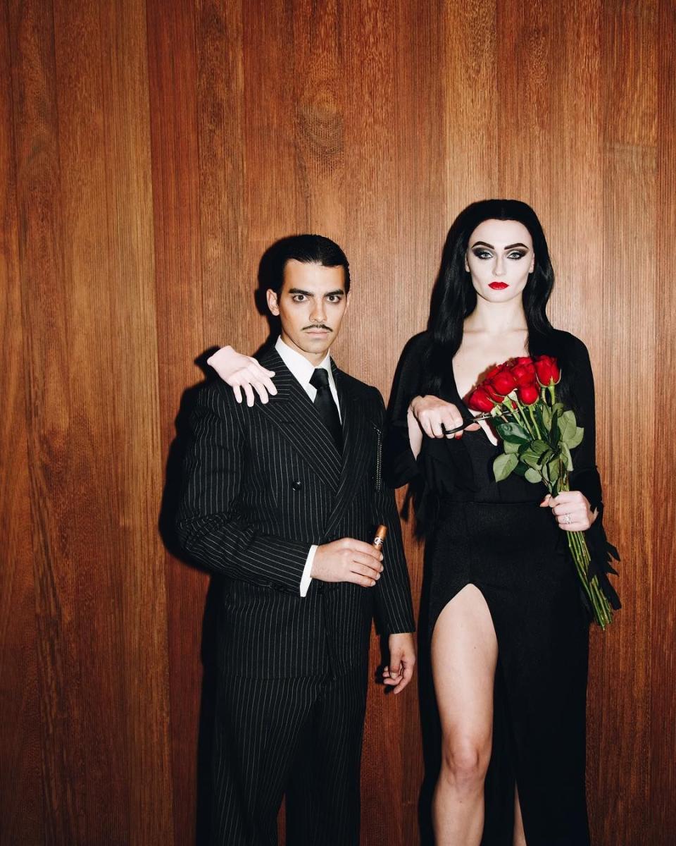 <p>The newlyweds perfectly executed the "all together ooky" parents of the <a href="https://www.goodhousekeeping.com/holidays/halloween-ideas/g28589490/best-wednesday-addams-costume-ideas/" rel="nofollow noopener" target="_blank" data-ylk="slk:Addams family;elm:context_link;itc:0;sec:content-canvas" class="link ">Addams family</a>. They even managed to include Thing in their costume!</p>