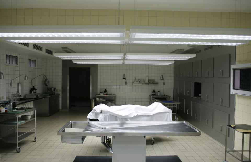 A body wrapped in plastic lies in the middle of a hospital morgue