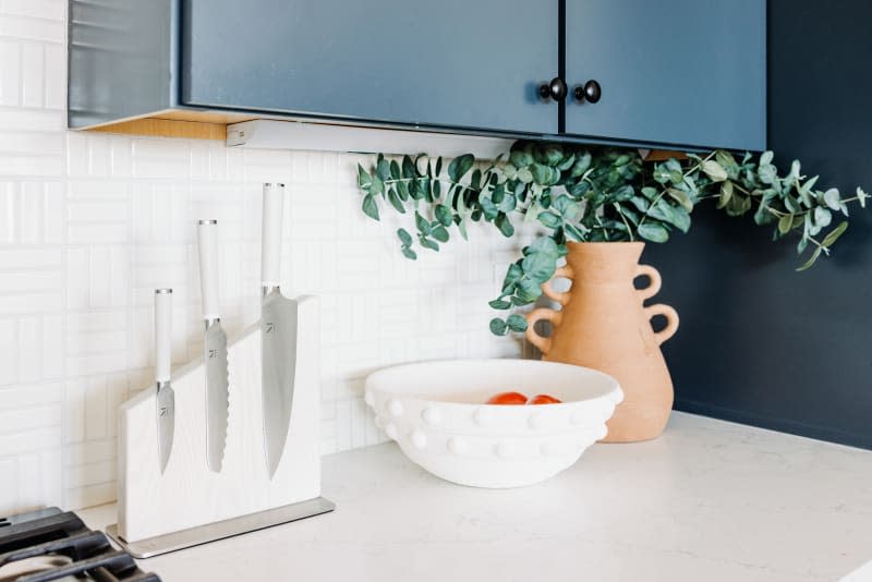 detail of counter area, knife block, and blue cabinet in white kitchen