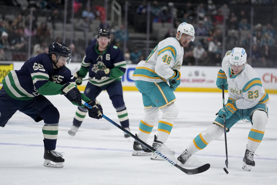 San Jose Sharks left wing Oskar Lindblom (23) and Vancouver Canucks right wing Ilya Mikheyev (65) compete for possession of the puck during the second period of an NHL hockey game in San Jose, Calif., Wednesday, Dec. 7, 2022. (AP Photo/Godofredo A. Vásquez)