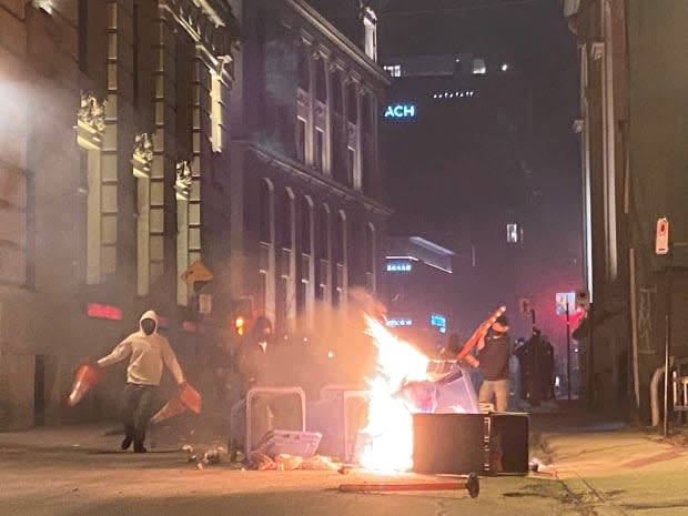 Some protesters lit fires in garbage cans and on the street, while others set off fireworks and chanted slogans deriding Premier François Legault. (Giuseppe Valiante/The Canadian Press - image credit)