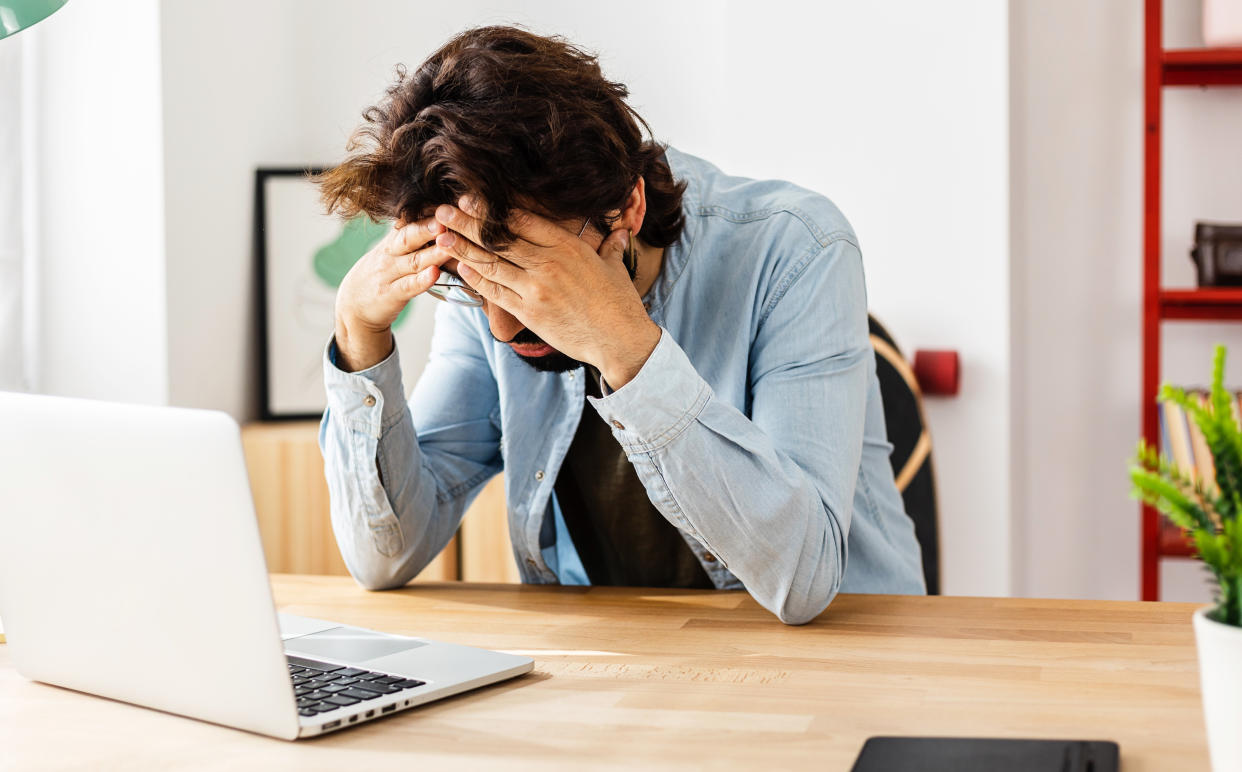 Young professional freelancer man looking worried and stressed over work while sitting on a desktop at home office. Business concept.