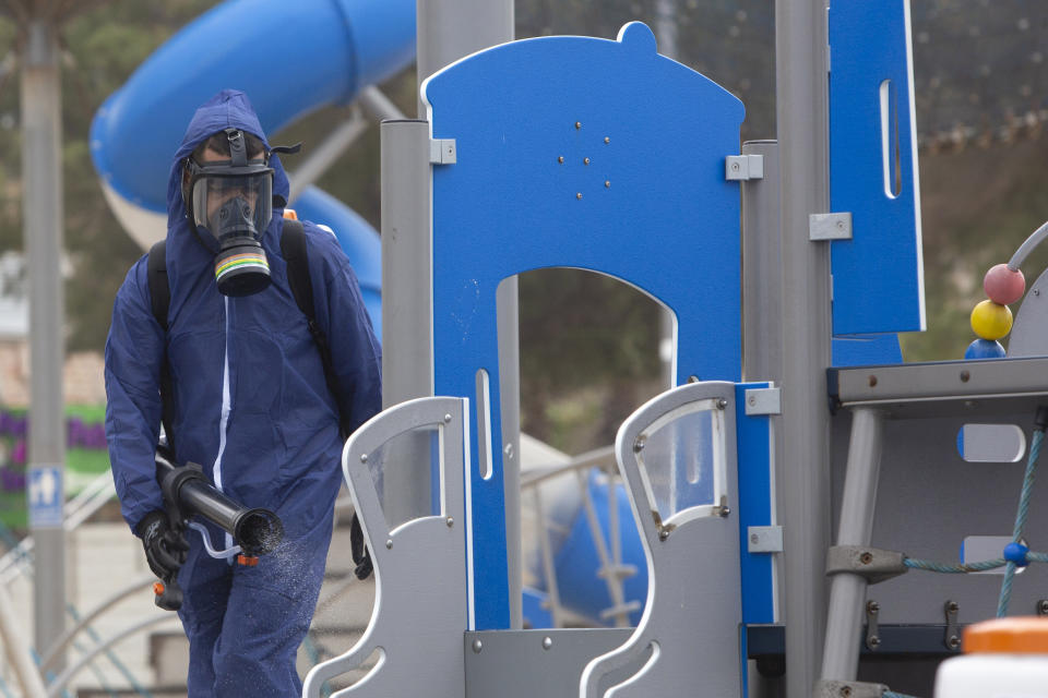 A worker sprays disinfectant as a precaution against the coronavirus in a playground in the central Israeli city of Bat Yam, Wednesday, March 18, 2020. Israel braced for its first fatalities as the number of coronavirus cases spiked by 25% on Wednesday. For most people, the virus causes only mild or moderate symptoms. For some it can cause more severe illness. (AP Photo/Sebastian Scheiner)