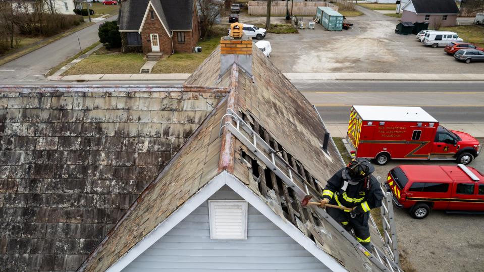 New Philadelphia firefighter Lt. Bobby Smith practices punching holes in a slate roof during a training exercises at a home on West High Avenue in New Philadelphia.