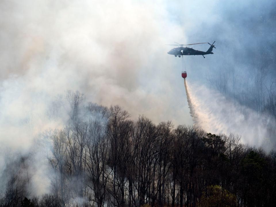 A Tennessee National Guard Blackhawk helicopter drops nearly 600 gallons of water onto the Cold Springs Hollow Road fire in Seymour, Tenn. on Sunday, April 3, 2022. 
