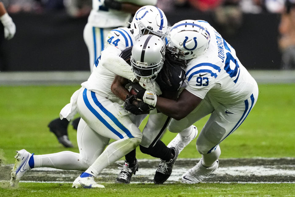 Las Vegas Raiders wide receiver Davante Adams (17) is tackled by Indianapolis Colts linebacker Zaire Franklin (44) and defensive tackle Eric Johnson II in the first half of an NFL football game in Las Vegas, Sunday, Nov. 13, 2022. (AP Photo/Matt York)
