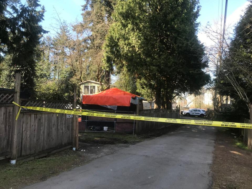 Part of the property in the 13300 block of 98A Avenue is covered with an orange tarp behind crime scene tape after a hostage-taking left two people dead inside the home on Friday, March 29, 2019.