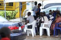 Customers sit under tent canopies outside a bank in area 8, in Abuja