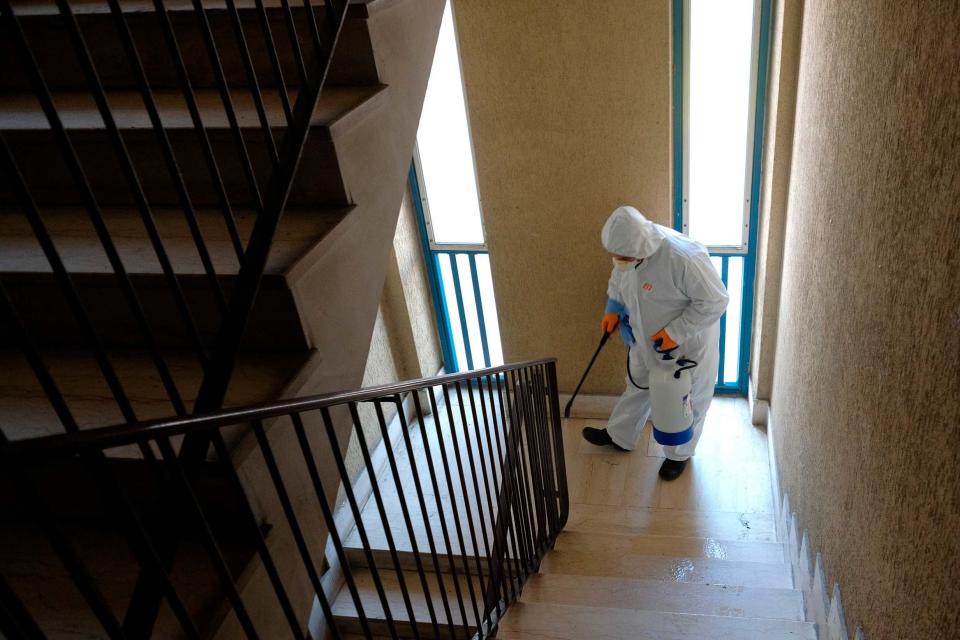 A man wearing a protective suit cleans the stairway in the neighborhood of Spinaceto, on the outskirts of Rome (AP)