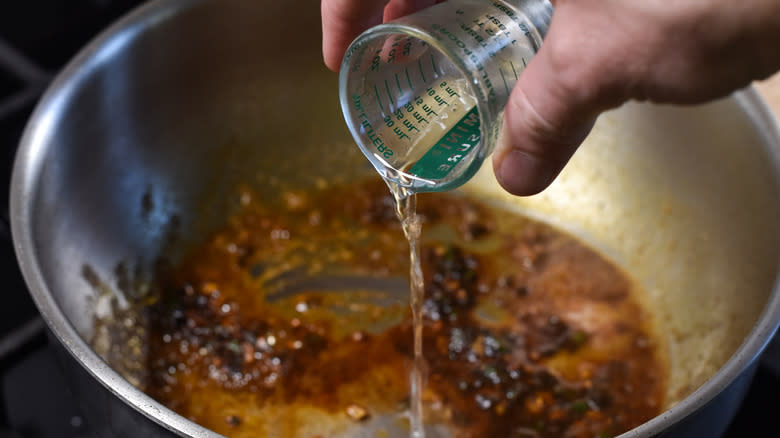 pouring mezcal into pot