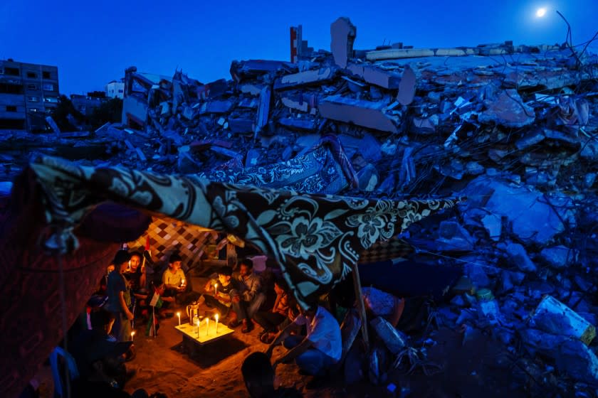 GAZA CITY, PALESTINIAN TERRITORY -- MAY 25, 2021: Dozens of Palestinian children and family members attend a candlelight vigil to condemn the killing of children and civilians, which is held over the rubble of homes destroyed by Israeli military strike during the 11-day escalation between Israel and Gaza military factions, which has now ended after an Egyptian-brokered ceasefire, bringing a momentary peace and calm to grieve and recover what was lost in Gaza City, Tuesday, May 25, 2021. In the same rubble, members of two members of the Al-Madhoun family were killed ( Abdul Rahim Mohammed Madhoun (63) and his wife: Haijar Abu Sharkh al-Madhoun (60), al- al-Tanani family N wife, husband and four children, were killed in an Israeli airstrike hit their houses in the dawn of the first day of Eid, on 13 May 2021, in addition to 7 family members of Al-Malfouh family were rescued from under the rubble of the same strike. 248 Palestinians were killed during this escalation, including 66 children. Egypt pledged to provide $ 500 million in aid to Gaza to contribute to the reconstruction of the Gaza Strip. (MARCUS YAM / LOS ANGELES TIMES)