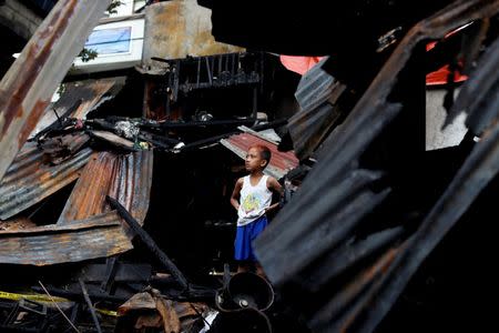 A boy stands in the ruins of his family's house gutted by a fire at a residential district in Pasig, Metro Manila, Philippines, May 5, 2018. REUTERS/Erik De Castro