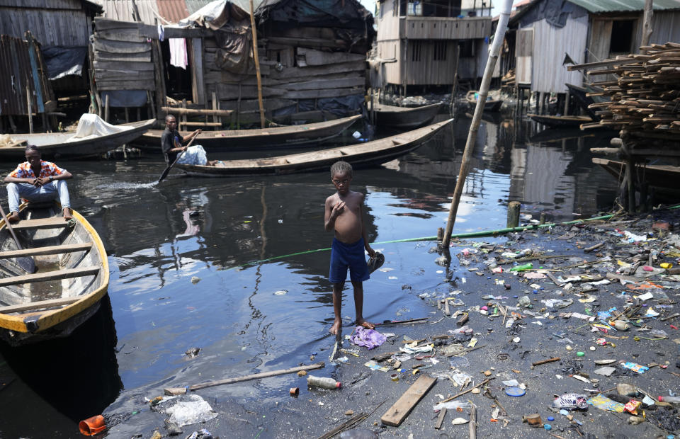 A child stands in filthy water surrounded by garbage in Nigeria's economic capital Lagos' floating slum of Makoko, Monday, March. 20, 2023. March 22 is World Water Day, established by the United Nations and marked annually since 1993 to raise awareness about access to clean water and sanitation. (AP Photo/Sunday Alamba)