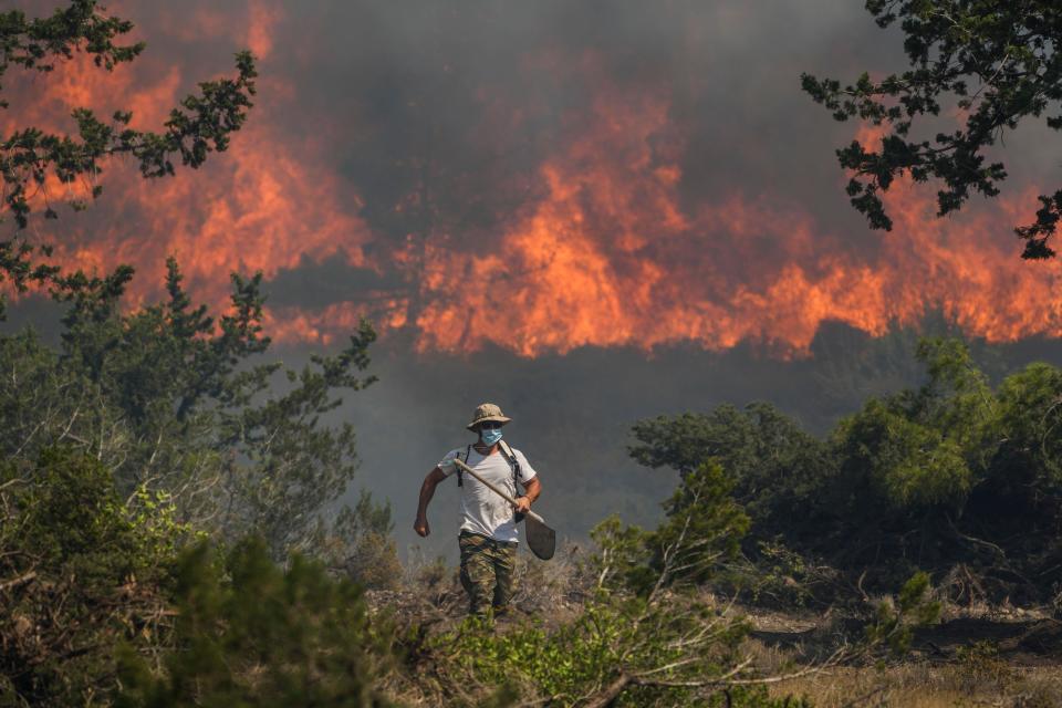 Flames burn a forest in Vati village, on the Aegean Sea island of Rhodes, southeastern Greece, on Tuesday, July 25, 2023. A third successive heat wave in Greece pushed temperatures back above 40 degrees Celsius (104 degrees Fahrenheit) across parts of the country Tuesday following more nighttime evacuations from fires that have raged out of control for days. (AP Photo/Petros Giannakouris)