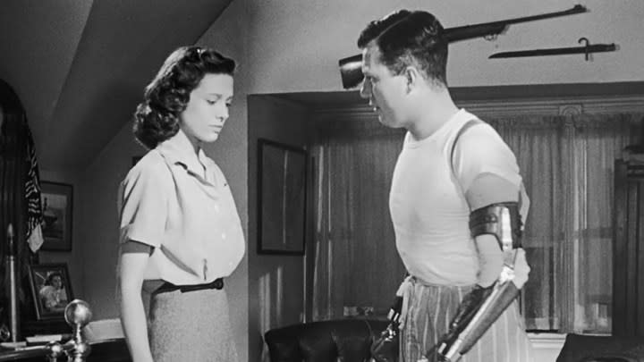 A black and white image of Harold Russell standing beside a woman in a scene from The Best Years of Our Lives.