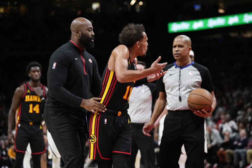 Atlanta Hawks guard Trae Young (11) is restrained after his was ejected during the second half of an NBA basketball game, Monday, Dec. 11, 2023, in Atlanta. (AP Photo/John Bazemore)