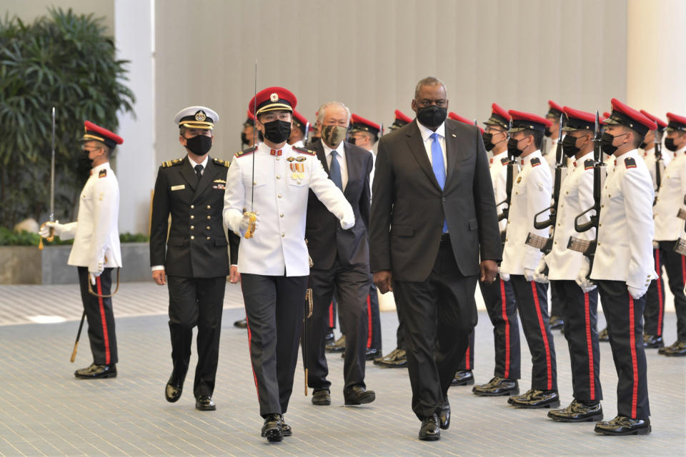 In this photo provided by the Singapore Ministry of Defense, U.S. Defense Secretary Lloyd J. Austin along with Singapore Defense Minister Ng Eng Hen, back, review an honor guard at the Ministry of Defense Tuesday, July 27, 2021 in Singapore. Austin decried the actions of Myanmar's military rulers as unacceptable on Tuesday, while urging a regional bloc to keep demanding an end to violence. Austin also applauded the Association of Southeast Asian nations for its efforts on the issue, which included forging a consensus with Myanmar’s military leader in April. (Singapore Ministry of Defense via AP)