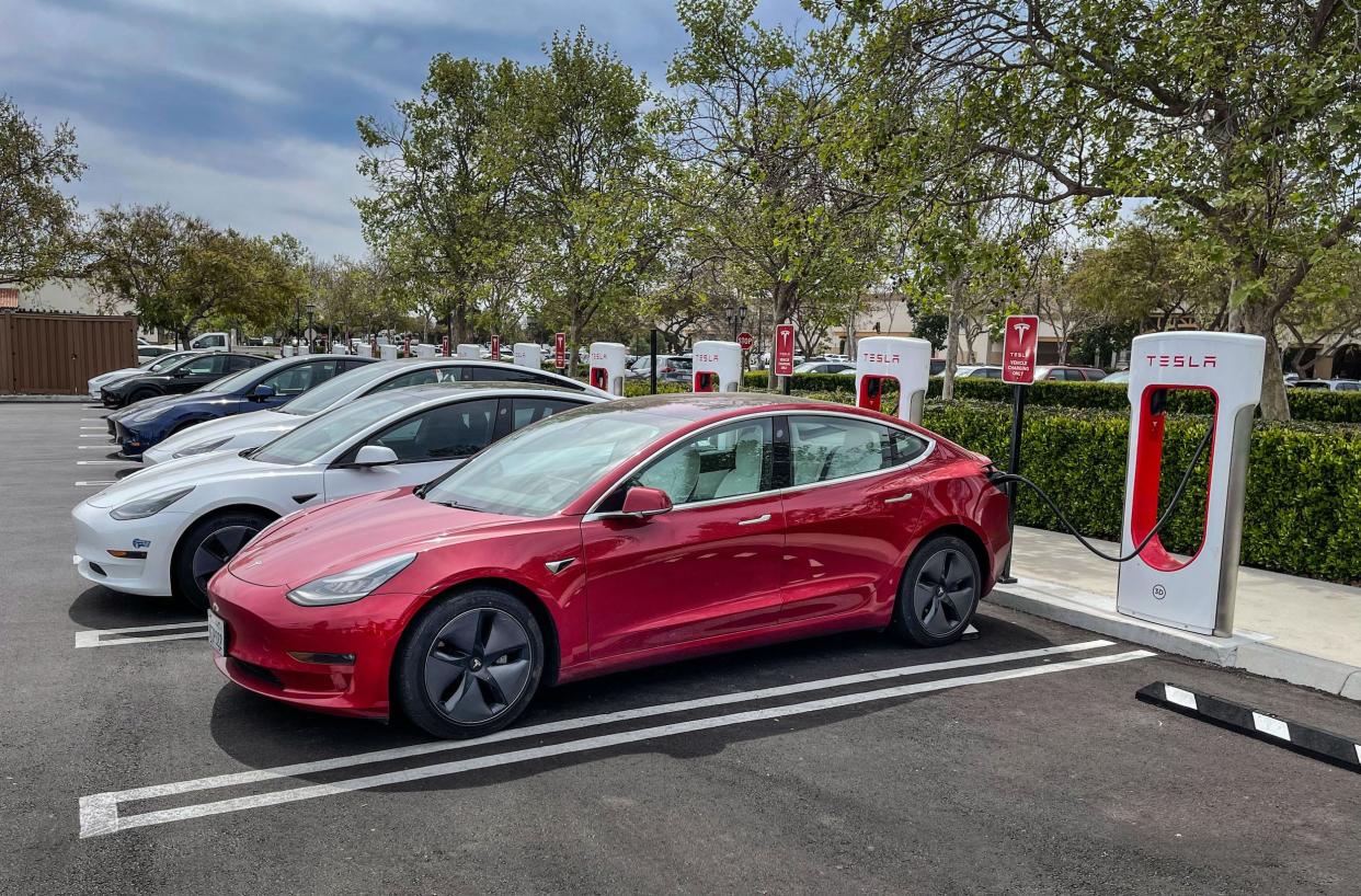 Tesla electric cars charge at a Supercharger.