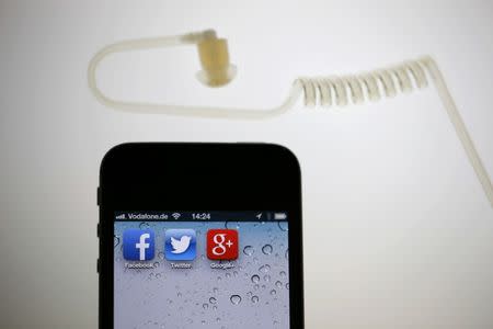 FILE PHOTO - The application icons of Facebook, Twitter and Google are displayed on an iPhone next to an earphone set in this illustration photo taken in Berlin, June 17, 2013. REUTERS/Pawel Kopczynski