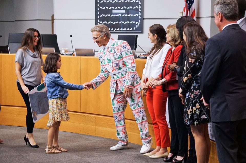School Board Chairman Frank Barbieri congratulates fifth-grader Camille Zambrano for her winning submission to this year's holiday greeting card contest.
